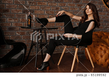 Glamour sexy young confident woman with long hair sitting with legs on table 65199592