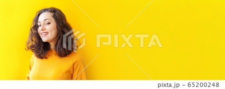 Happy girl smiling. Beauty portrait young happy positive laughing brunette woman on yellow background isolated. European woman. Positive human emotion facial expression body language Banner Happy girl smiling. Beauty portrait young happy positive laughing brunette woman on yellow background isolated. European woman. Positive human emotion facial expression body language Banner 65200248