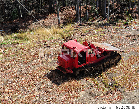 A red tractor stands on gray gravel ground among 65200949