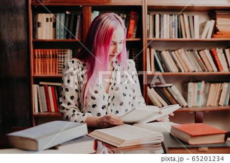 girl reading a book in the library is preparing for exams girl reading a book in the library is preparing for exams 65201234