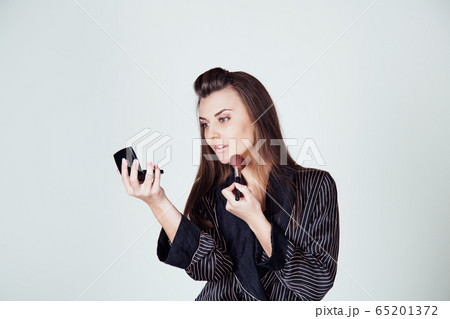 girl in coat makes brush makeup looks in the mirror 65201372