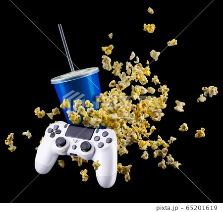 Flying popcorn, cup of soft drink and video game joystick isolated on black 65201619