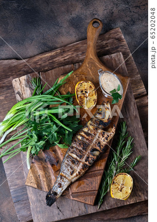 Grilled trout served on a cutting board. On wooden background. Top view 65202048