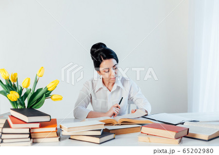 women in a business suit behind a table with books women in a business suit behind a table with books 65202980