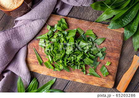 Cutting up fresh ribwort plantain leaves, to prepare herbal syrup 65203286