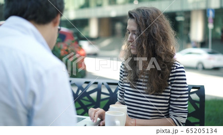Young woman in striped shirt and her handsome colleague in white shirt working together in summer Young woman in striped shirt and her handsome colleague in white shirt working together in summer 65205134