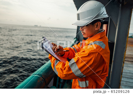 Filipino deck Officer on deck of offshore vessel or ship fills checklist. Paperwork at sea Filipino deck Officer on deck of offshore vessel or ship fills checklist. Paperwork at sea 65209126