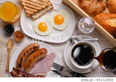 Pouring coffee on a cup with breakfast on wooden table Pouring coffee on a cup with breakfast on wooden table 65212808