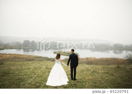 Wedding couple holding hands, groom and bride together on wedding day Wedding couple holding hands, groom and bride together on wedding day 65220791