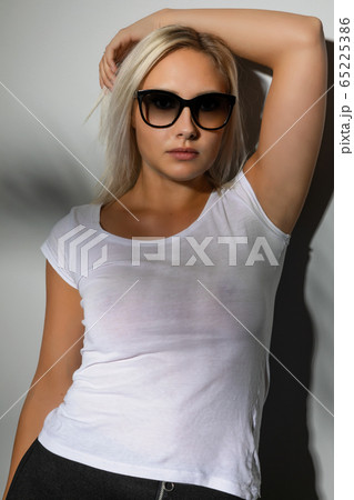 Gorgeous blonde woman with sunglasses in light and shadow Gorgeous blonde woman with sunglasses in light and shadow 65225386