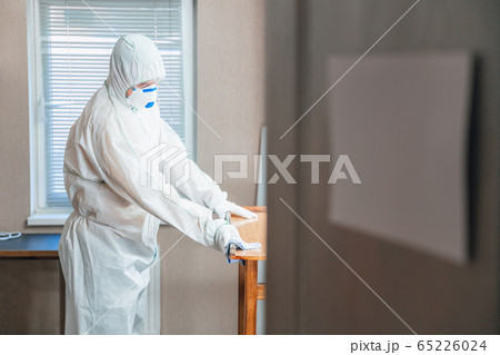 Coronavirus Pandemic. A disinfector in a protective suit and mask sprays disinfectants in the house or office Coronavirus Pandemic. A disinfector in a protective suit and mask sprays disinfectants in the house or office 65226024