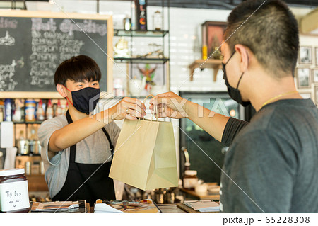 Social distance conceptual waiter giving takeaway bag to customer at cafe. Social distance conceptual waiter giving takeaway bag to customer at cafe. 65228308