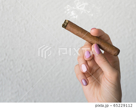Woman hand holding a burning cigar. Woman hand holding a burning cigar. 65229112