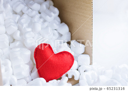 Red felt heart packaging box filled many white styrofoam pellets.  65231316