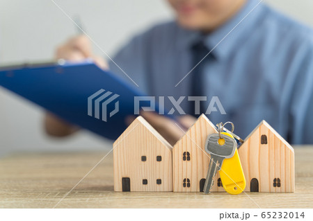 House Wooden model and Key in real estate , seller or buyer , loan concept with blur loan employee or realtor he's checking details about the sale of the house ,home Mortgage or home lone 65232014