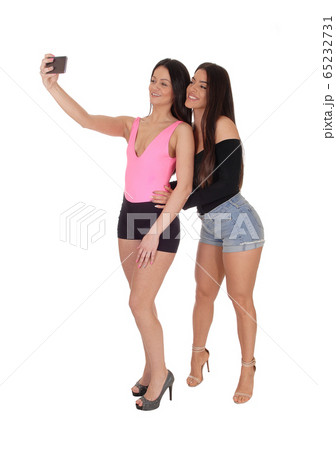 Two beautiful women standing in shorts talking a 65232731
