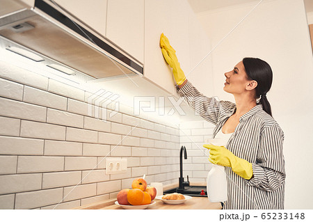 Positive delighted female person cleaning her kitchen 65233148