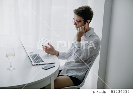 Happy young man, wearing glasses and smiling, as he works on his laptop. Man in quarantine works at home. Stay at home. 65234353