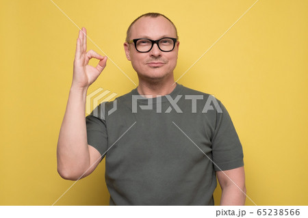 Cheerful young man showing okay gesture, approving his choice Cheerful young man showing okay gesture, approving his choice 65238566