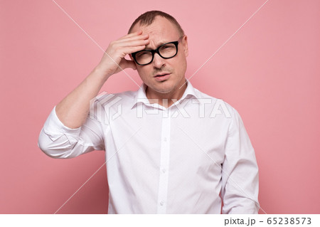 Stressed young man in eyeglasses regretting about something, looking at camera. Stressed young man in eyeglasses regretting about something, looking at camera. 65238573
