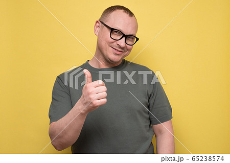 mature man gesturing thumb up approving your choice on yellow wall. mature man gesturing thumb up approving your choice on yellow wall. 65238574