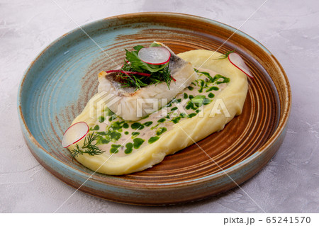 Cod with mashed potatoes, zucchini grill and sauce on the light background. European cuisine. The Cod with mashed potatoes, zucchini grill and sauce on the light background. European cuisine. The 65241570
