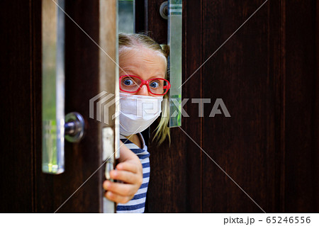 Child wearing face masks peeking out the door 65246556