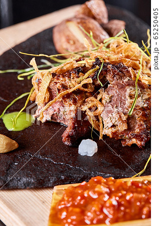 Grilled Beef steak Ribeye with roasted potato on cutting board. With deep-fried onions and tomato sauce. Grilled Beef steak Ribeye with roasted potato on cutting board. With deep-fried onions and tomato sauce. 65250405