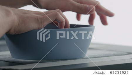 man hands sand bottom of blue ceramic bowl 65251922