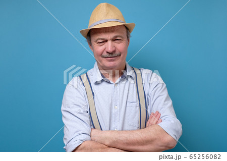 Serious senior man in summer hat posing with folded hands. 65256082