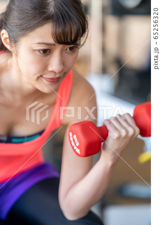 ダンベルで腕の筋肉上腕三頭筋を鍛える真剣な表情の若い女性の写真素材