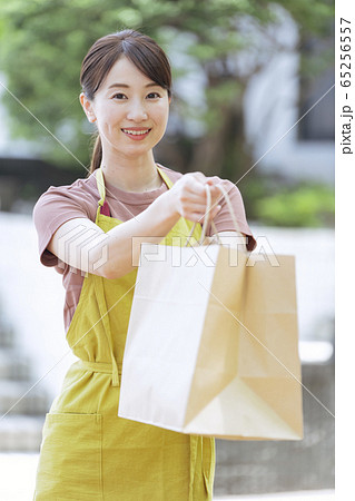 テイクアウトの紙袋を渡す飲食店員 65256557