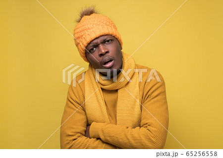 African man in warm hat and scarf looking at camera with confused expression 65256558