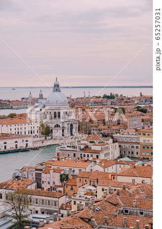 Aerial view from huge cathedral bell tower St Mark's Campanile on Santa Maria - Della - Salute - Church in the name of St. Mary the Savior, sunset sky and orange roof tiles. Venice, Italy  65257031