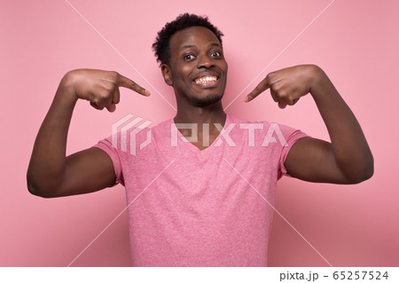 Positive young african man smiling and pointing at himself with index fingers. 65257524