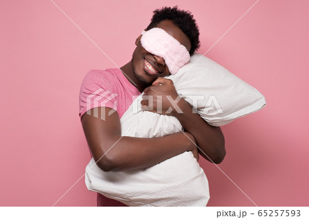 african american black man sleeping hugging a pillow wearing sleeping mask. 65257593