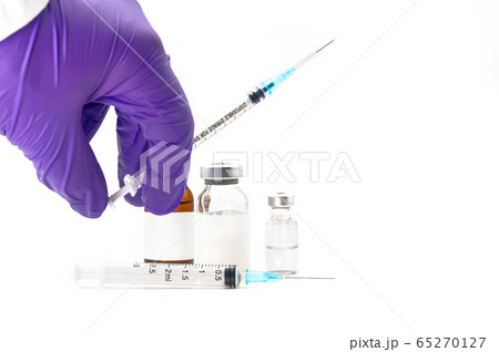 Pharmaceutical Scientist picking up a syringe. Coronavirus vaccine research. Medicine vials in white Pharmaceutical Scientist picking up a syringe. Coronavirus vaccine research. Medicine vials in white 65270127