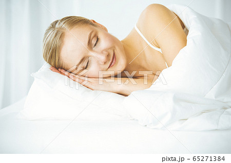 Beautiful young woman sleeping in bedroom comfortably and blissfully. Waking up in happy morning 65271384