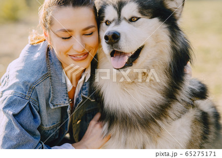 Stylish girl in a spring field with a dog Stylish girl in a spring field with a dog 65275171