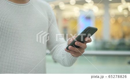 Man s hand scrolling a phone on blurred yellow background 65278826