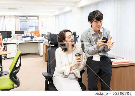 オフィスで話をする女性上司と若い男性社員 オフィスで話をする女性上司と若い男性社員 65286705