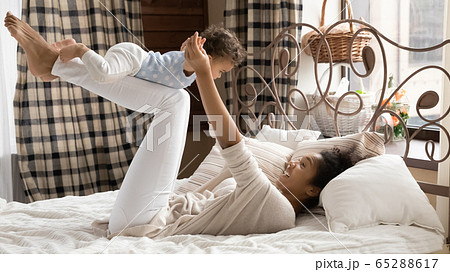 Happy biracial mom playing with little baby 65288617