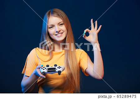 Happy girl holding video game joystick showing OK sign 65289475