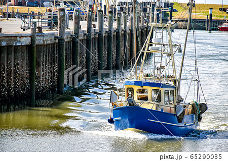 A small fishing boat enters the harbour of Busum in North Frisia in Germany. A small fishing boat enters the harbour of Busum in North Frisia in Germany. 65290035