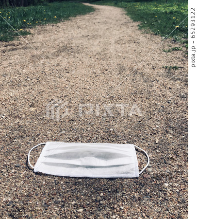A white medical mask used to fight the coronavirus was left on the road. 65293122