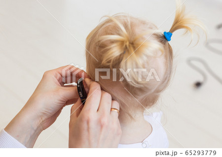 Hearing aid in baby girl's ear. Toddler child wearing a hearing aid at home. Disabled child, disability and deafness concept. Hearing aid in baby girl's ear. Toddler child wearing a hearing aid at home. Disabled child, disability and deafness concept. 65293779