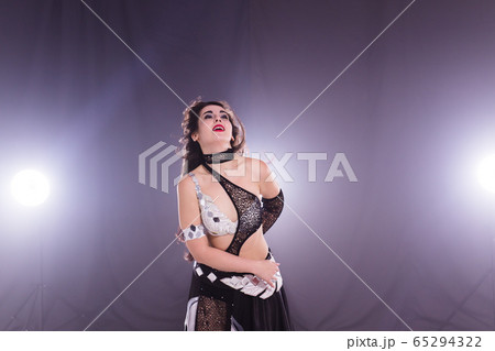 Young woman belly dancer in exotic dress with gold, dancing tribal fusion dance in studio. 65294322
