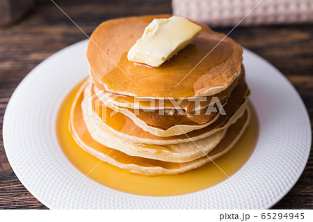 Golden pancakes with butter and warm maple syrup. 65294945