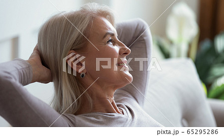 Calm mature woman relax on couch daydreaming 65295286