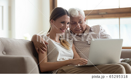 Happy senior dad and adult daughter using laptop together 65295318